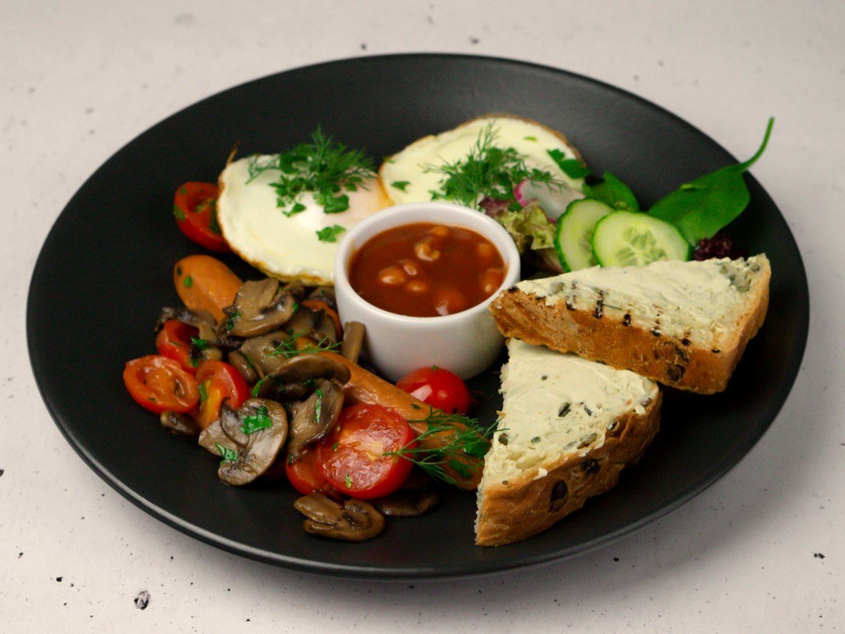 English breakfast plate with fried eggs, beans in tomato sauce, mushrooms and toast